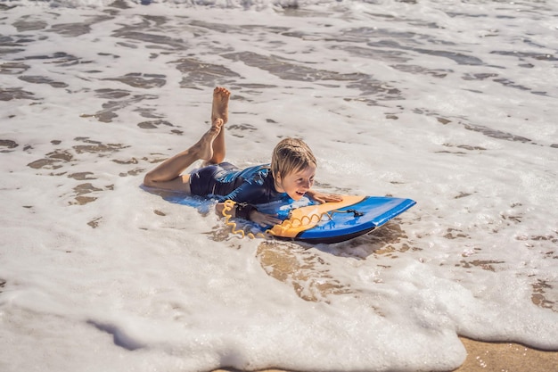 Giovane ragazzo felice che si diverte in spiaggia in vacanza con la tavola Boogie