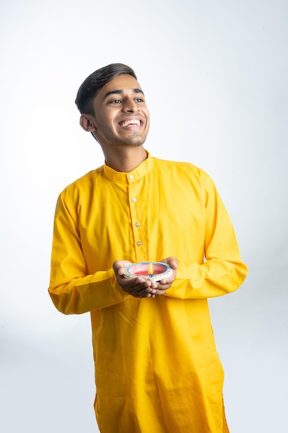 Giovane ragazzo indiano che tiene Diya per Diwali e indossa il tradizionale