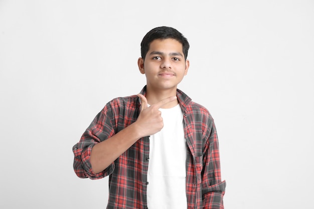 Giovane ragazzo indiano in un abbigliamento casual e che mostra l'espressione sul muro bianco