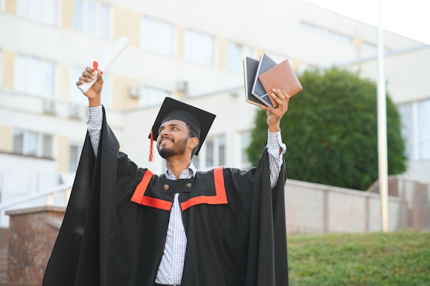 Giovane ragazzo laureato indiano che tiene la sua posizione laureata dello studente di cerimonia di convocazione di grado di laurea