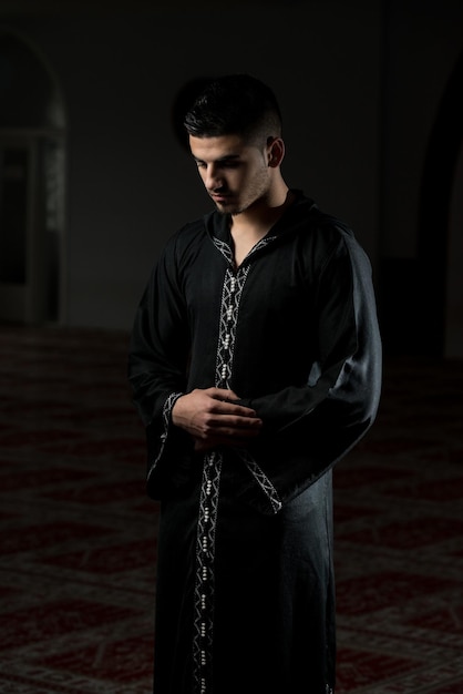 Giovane ragazzo musulmano che fa la tradizionale preghiera a Dio mentre indossa un tradizionale cappuccio Dishdasha