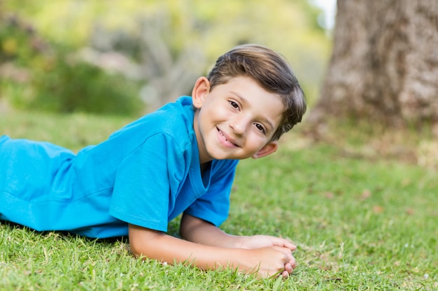 Giovane ragazzo sorridente che si trova sull'erba