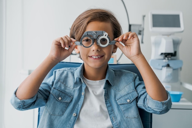 Giovane ragazzo sottoposto a prova della vista con gli occhiali in clinica medica