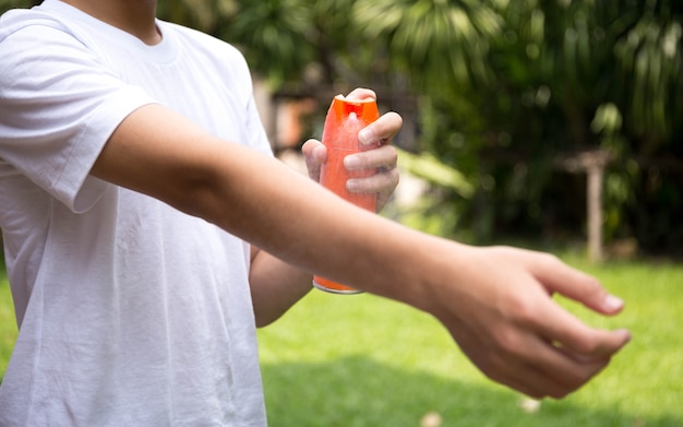 Giovane ragazzo spruzzare repellenti per insetti sulla pelle con flacone spray