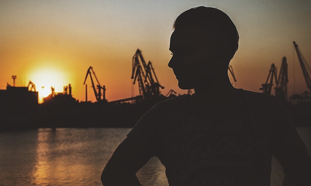 Giovane ragazzo sullo sfondo del porto al tramonto. sera d'estate. atmosfera oscura