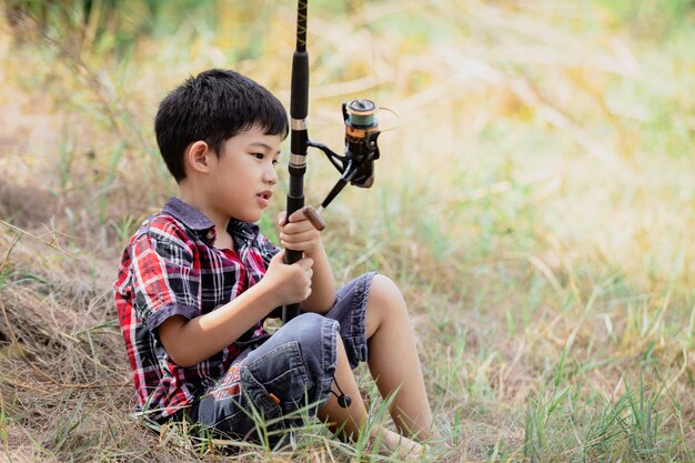 Giovane ragazzo sveglio asiatico che pesca in naturale