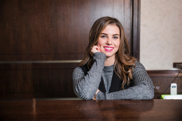 Giovane receptionist femminile al suo scrittorio che guarda l&#39;obbiettivo