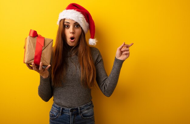 Giovane regalo grazioso della tenuta della donna che indica il lato