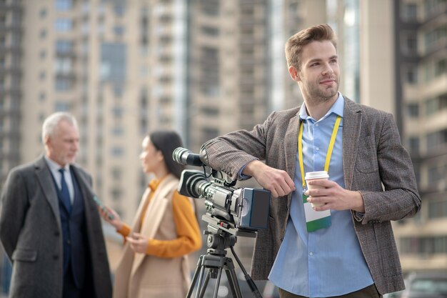 Giovane reporter bello che mangia caffè che si sente bene durante la pausa nel lavoro