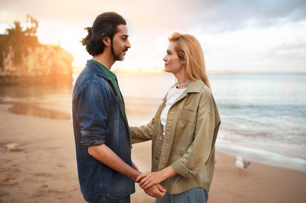 Giovane romantico e donna in piedi sulla spiaggia al tramonto