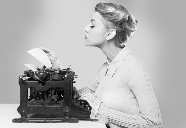 Giovane scrittrice bionda che utilizza macchina da scrivere, ritratto in bianco e nero