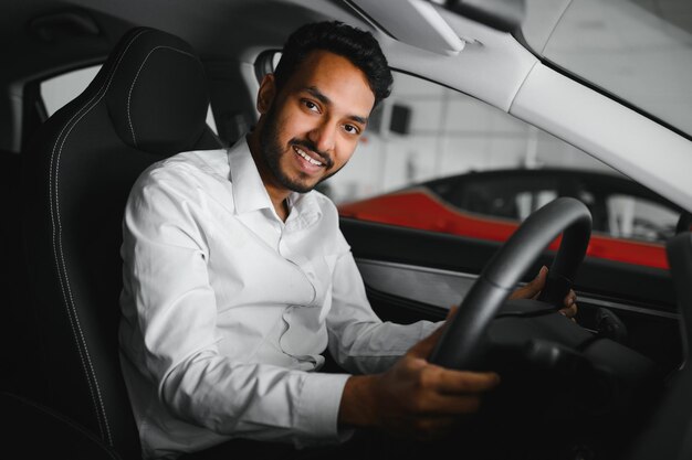 Giovane seduto all'interno di un'auto nuova Sorridente