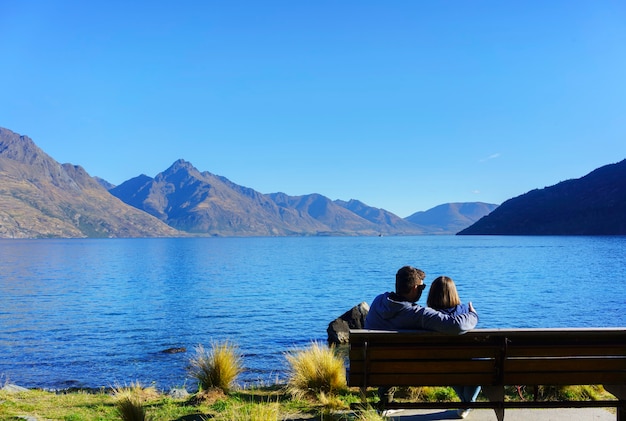 Giovane seduto sulla sedia nel giardino di Queenstown, rilassante con l'atmosfera del lago Wakatipu in autunno, Queenstown, Isola del Sud della Nuova Zelanda