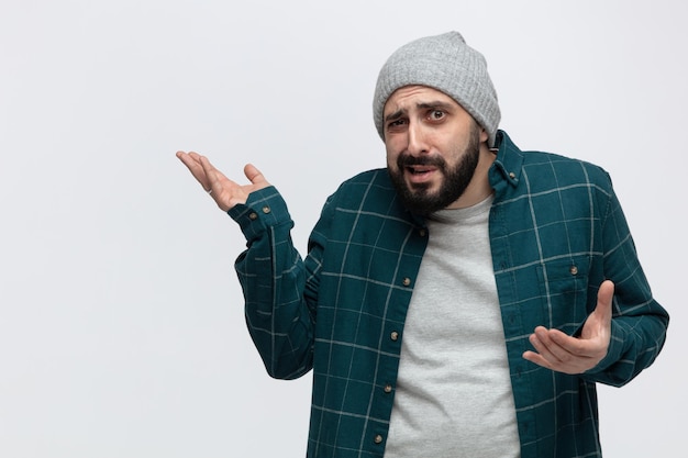 Giovane senza tracce che indossa un cappello invernale guardando la fotocamera che mostra le mani vuote isolate su sfondo bianco