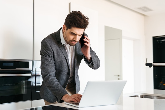 Giovane serio in vestito che comunica sul telefono cellulare