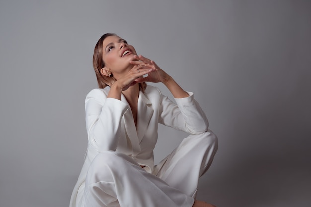 Giovane signora alla moda in un ritratto di tailleur pantalone bianco in studio