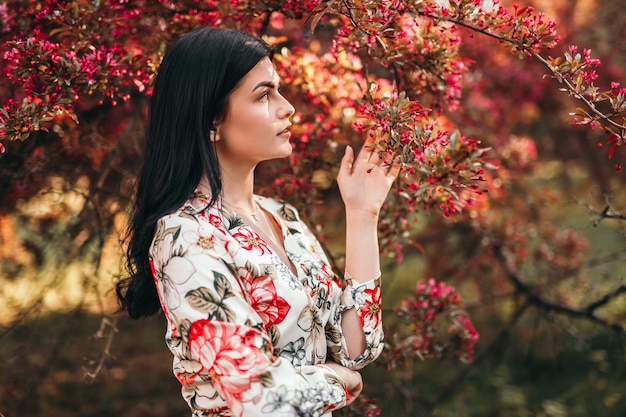 Giovane signora che tocca l'albero in fiore nel parco