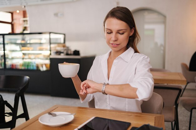 Giovane signora di affari che lavora nel caffè donna attraente nel ritratto convenzionale della camicia bianca