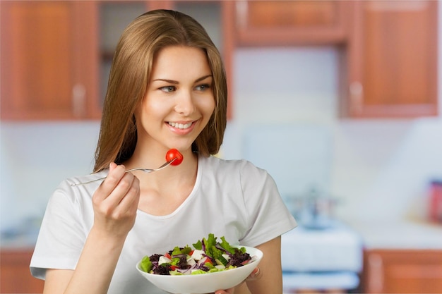 Giovane signora felice che mangia insalata