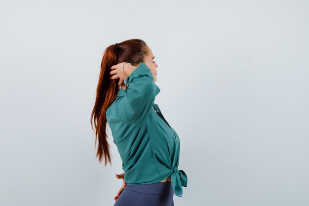 Giovane signora in posa con la testa dietro la testa in camicia verde e dall'aspetto affascinante.