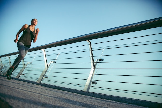 Giovane signora sportiva esile che corre sul ponte. Banner del sito web