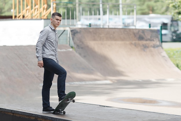 Giovane skateboarder maschio che si prepara a guidare lo sketchboard sollevandolo con un piede nel parco in una calda giornata estiva