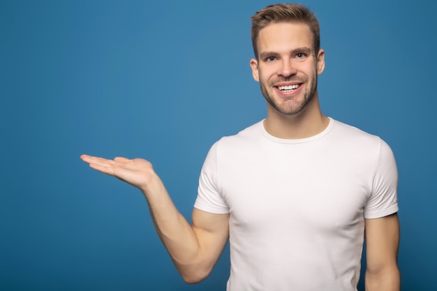 giovane sorridente che indica con la mano da parte isolata sull'azzurro