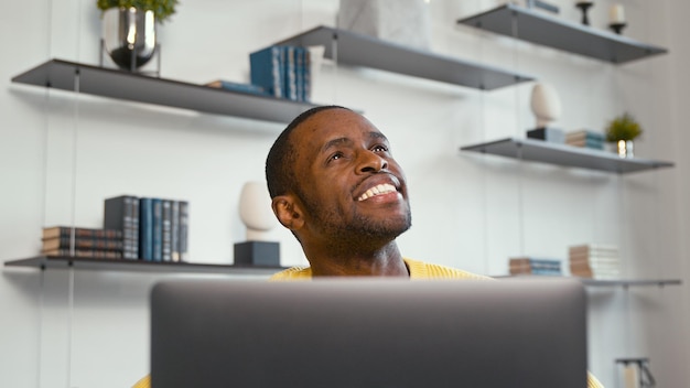 Giovane sorridente che lavora con il computer portatile a casa