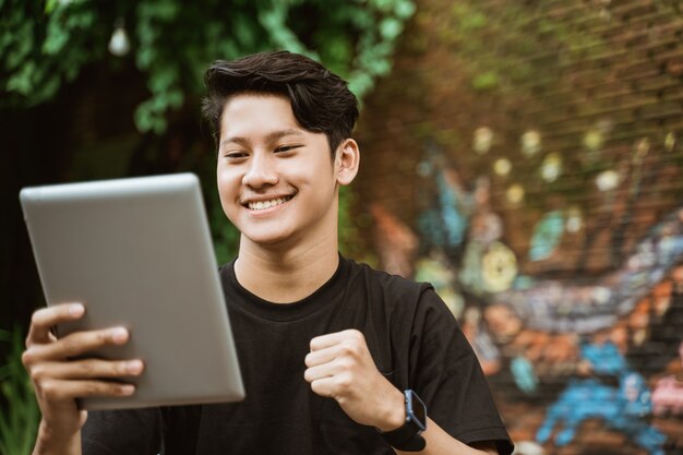 Giovane sorridente che per mezzo del pc della compressa