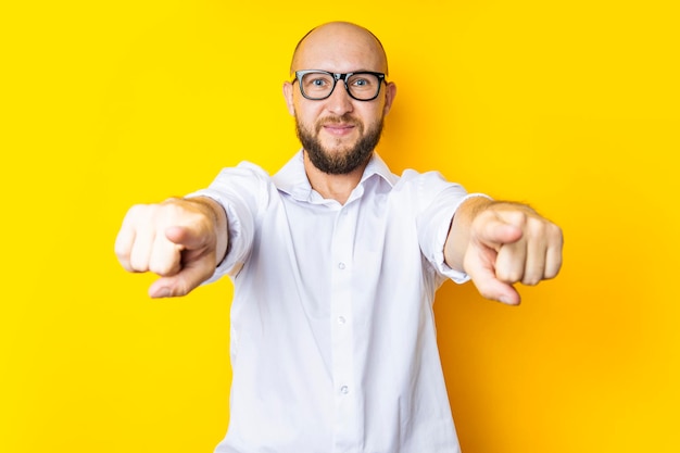 Giovane sorridente che punta le dita al visualizzatore su sfondo giallo