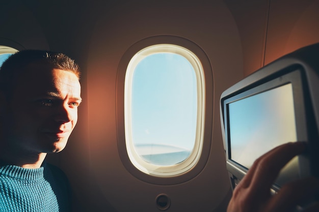 Giovane sorridente che usa la tecnologia mentre viaggia in aereo