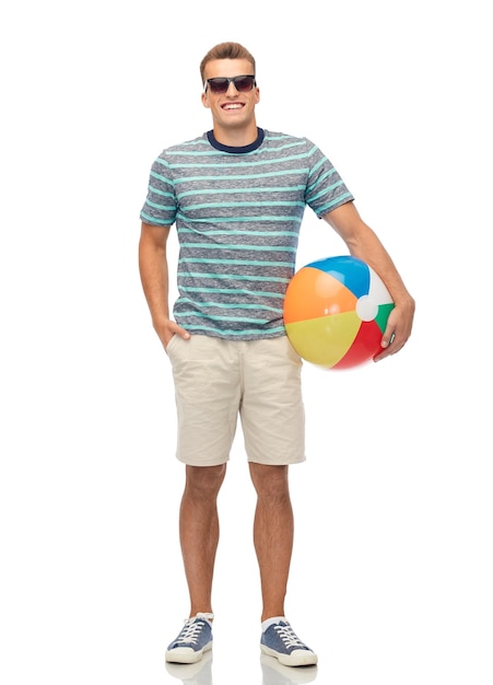 giovane sorridente con gli occhiali da sole e una palla da spiaggia