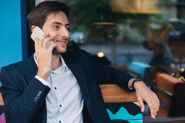 Giovane sorridente del ritratto che parla sul telefono cellulare