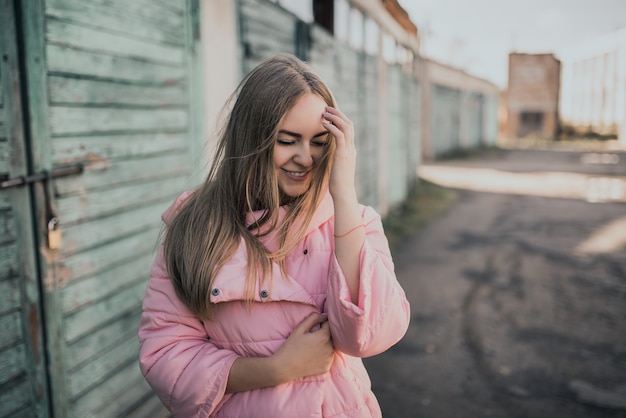 Giovane splendida ragazza bionda vestita moda giacca rosa e blue jeans.