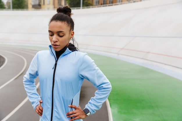 giovane sportiva africana che riposa dopo aver corso allo stadio