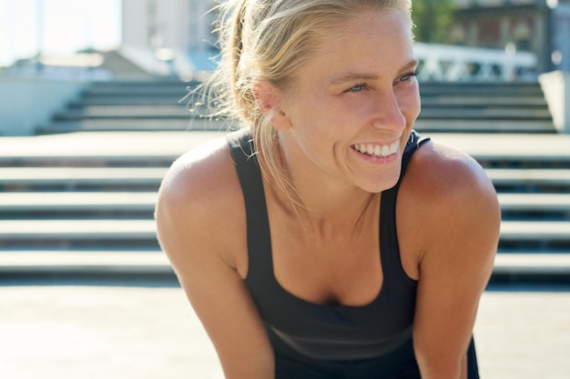 Giovane sportiva bionda allegra in abbigliamento sportivo nero che si gode la pausa