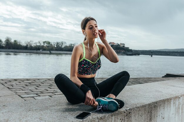 Giovane sportiva che riposa dopo un allenamento ascoltando la musica