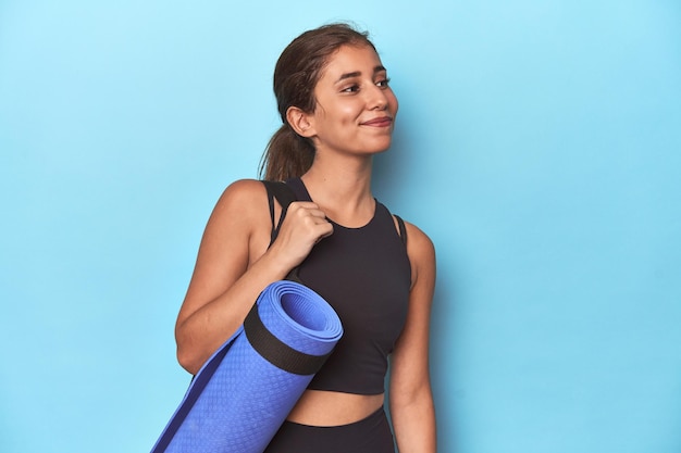 Giovane sportiva che tiene una stuoia di yoga in studio