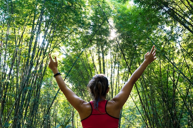 Giovane sportiva in buona salute con le braccia spalancate aperta nel mezzo della giungla