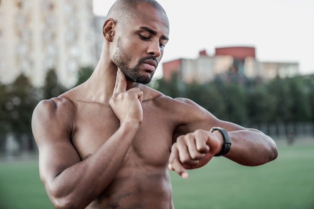 Giovane sportivo che controlla il polso con gli orologi dopo l'allenamento