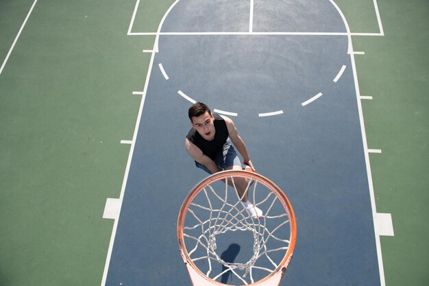 Giovane sportivo che gioca a basket sul campo da basket all'aperto