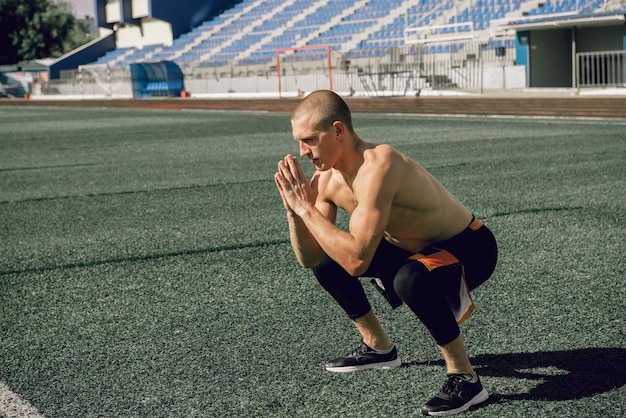 Giovane sportivo facendo esercizio squat allo stadio