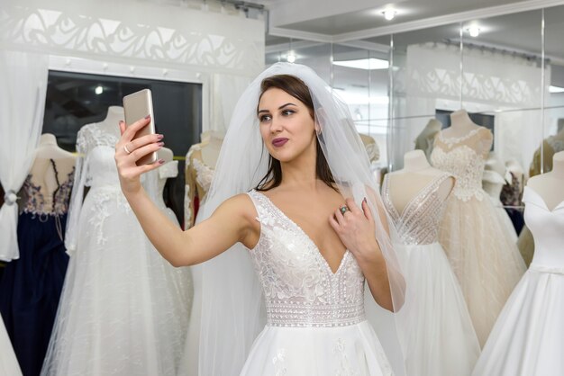 Giovane sposa che fa selfie in abito da sposa in salone