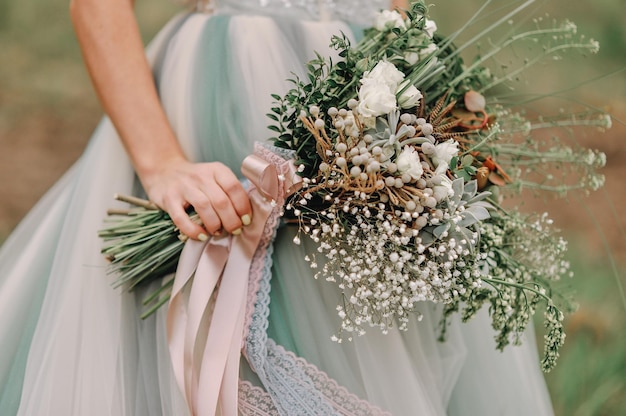 Giovane sposa dai capelli rossi che tiene un bouquet da sposa primaverile