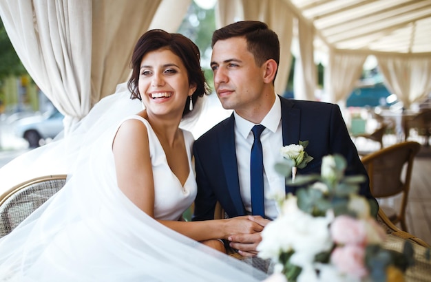 Giovane sposa e sposo in un caffè Marito e moglie si tengono per mano Coppia amorevole nel ristorante