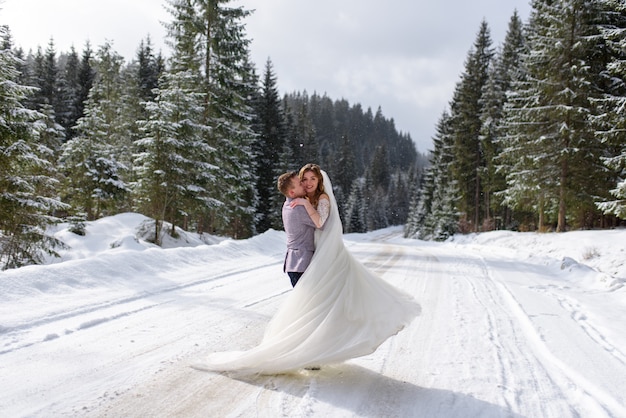 Giovane sposa e sposo sulla foresta nevosa