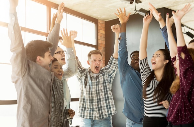 Giovane squadra di affari felice che gode del successo nell'ufficio del loft, copia spazio