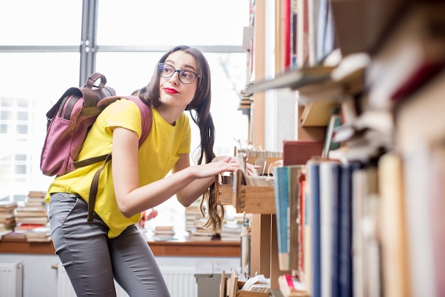 Giovane studente alla ricerca di libri con catalogo a schede presso la vecchia biblioteca o archivio