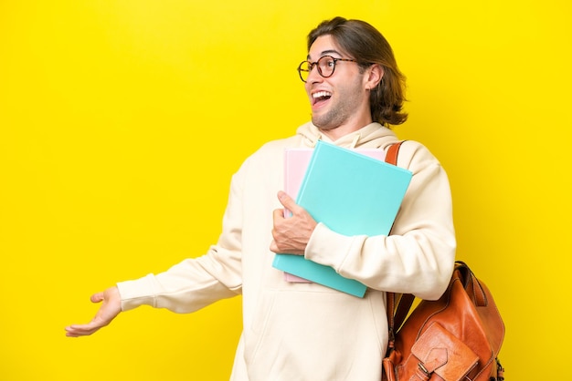 Giovane studente bell'uomo isolato su sfondo giallo con espressione sorpresa mentre guardava di lato