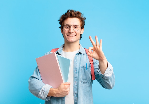 Giovane studente che si sente felice, rilassato e soddisfatto, mostrando approvazione con un gesto ok, sorridendo